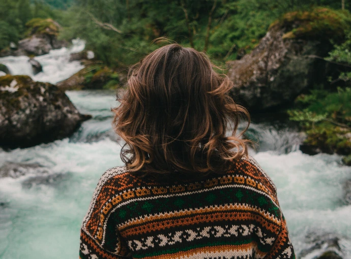 vrouw langs achter kijkt naar fel stromende rivier voor zich